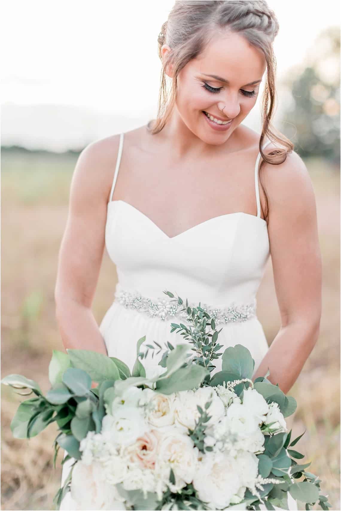 Smiling Bride with White Dress and White and Greenery Bouquet